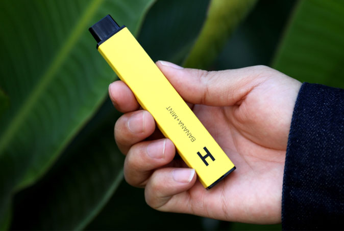 Person Holding Yellow Vape with Leafy Background 1 Person Holding Yellow Vape with Leafy Background 1